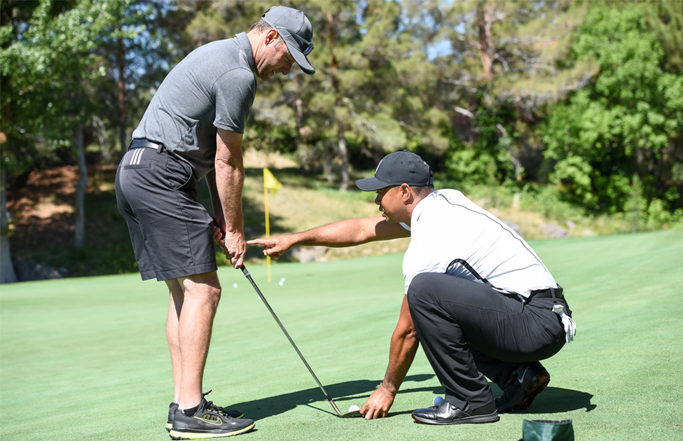 Chris Harrison gets a putting lesson from Tiger Jam host Tiger Woods